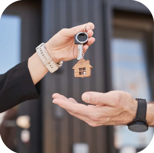 Landlord handing keys with a house keychain to a tenant